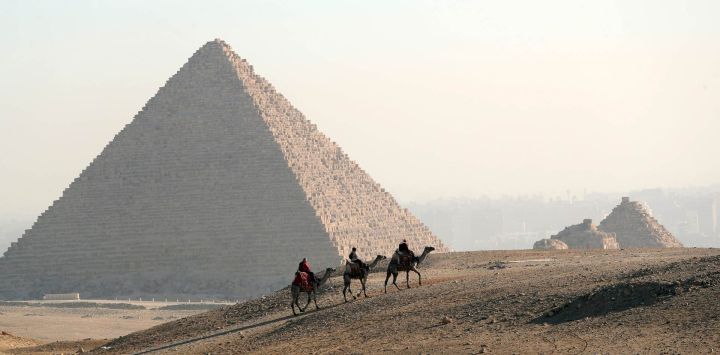 Turistas montan camellos en el punto escénico de las Pirámides, en Giza, Egipto.