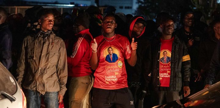Los partidarios del presidente electo de Zambia, Hakainde Hichilema, celebran su victoria en las calles tras el anuncio de la Comisión Electoral de Zambia en Lusaka. Reelegido para un segundo mandato al frente de Zambia, Hakainde Hichilema no pierde oportunidad de recordar su infancia como pastor de vacas descalzo en respuesta a las críticas que lo retratan como un magnate desconectado de la realidad y cada vez más inclinado a métodos de línea dura. El empresario de 64 años, a quien se le atribuye la reestructuración de la deuda del país y la gratuidad de la educación, ganó las elecciones con cerca del 60% de los votos, derrotando a Brian Mundubile, exministro del gobierno de Lungu (casi el 38%), quien solo pudo organizar una campaña de última hora.