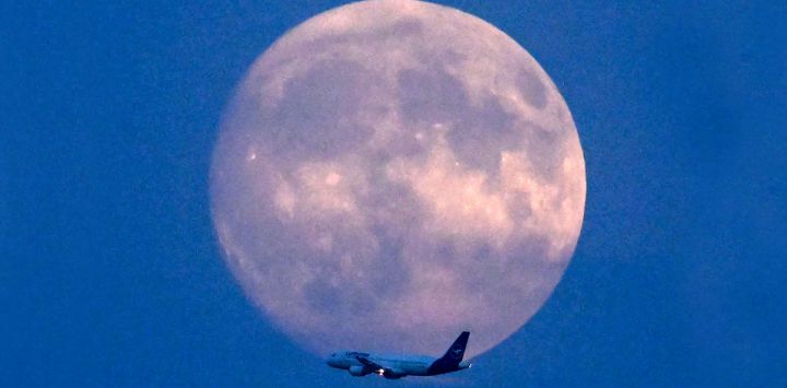 Un avión Airbus A320-214 de la aerolínea alemana Lufthansa sobrevuela la luna gibosa creciente sobre Fráncfort del Meno, en el oeste de Alemania.