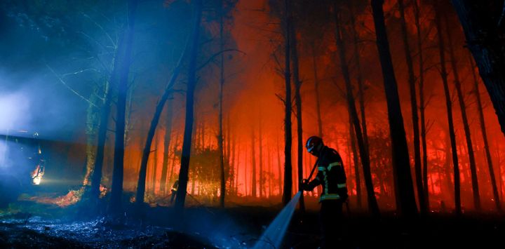 Un bombero rocía agua sobre el suelo carbonizado mientras las llamas continúan ardiendo en el bosque de las Landas, en Luglon, al suroeste de Francia.