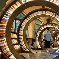 Una mujer visita una biblioteca creada a partir de una dolina, en el distrito de Wuyuan, en la provincia de Jiangxi, en el este de China. Una biblioteca especial creada en una dolina abrió recientemente al público en el distrito de Wuyuan, en la provincia de Jiangxi, en el este de China. Incorpora una dolina natural y paredes rocosas circundantes a su arquitectura. La biblioteca cuenta con una escalera de caracol tallada e iluminación cálida, ofreciendo a los visitantes una experiencia de lectura única. | Foto:Xinhua/Hu Chenhuan)