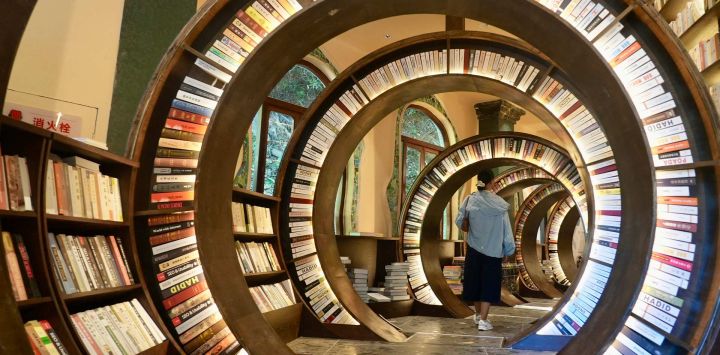 Una mujer visita una biblioteca creada a partir de una dolina, en el distrito de Wuyuan, en la provincia de Jiangxi, en el este de China. Una biblioteca especial creada en una dolina abrió recientemente al público en el distrito de Wuyuan, en la provincia de Jiangxi, en el este de China. Incorpora una dolina natural y paredes rocosas circundantes a su arquitectura. La biblioteca cuenta con una escalera de caracol tallada e iluminación cálida, ofreciendo a los visitantes una experiencia de lectura única.