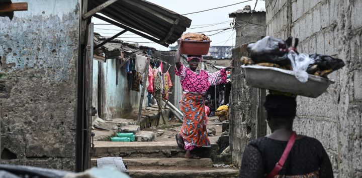 Residentes de Abiyán, en Abiyán, caminan con sus pertenencias sobre la cabeza. La población de Abiyán se ha duplicado en 20 años, superando los seis millones de habitantes, pero la oferta de vivienda sigue siendo insuficiente. Si bien Costa de Marfil ha experimentado un auge económico durante más de una década, el salario mínimo de 75.000 francos CFA (133 dólares) no alcanza para acceder a una vivienda digna.