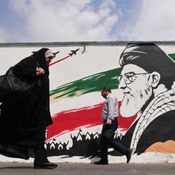 Los peatones pasan junto a un mural del asesinado líder supremo de Irán, el ayatolá Ali Jamenei, a lo largo de una calle en el centro de Teherán. Irán atacó objetivos militares estadounidenses en el Medio Oriente en represalia por los ataques estadounidenses en una isla en el Estrecho de Ormuz, el primer intercambio de disparos en un mes en una guerra que ha envuelto la región. Seis meses después del inicio del conflicto, las dos partes siguen en un punto muerto: Irán mantiene cerrado el estrecho estratégico y Washington persiste en un contrabloqueo naval contra Irán. | Foto:ATTA KENARE / AFP