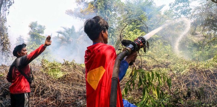 El estudiante indonesio Rudiansyah (derecha), vestido con un disfraz de Superman, ayuda a extinguir un incendio forestal en Petuk Katimpun, Palangkaraya, Kalimantan Central, Indonesia.