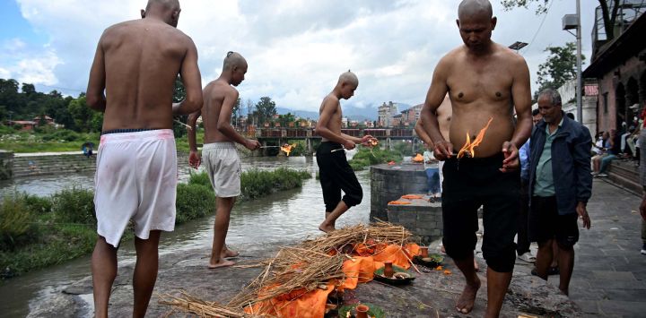 Familiares realizan ritos hindúes nepalíes para la cremación de efigies de hierba Kush durante funerales simbólicos celebrados en honor a las víctimas de las inundaciones que aún permanecen desaparecidas, en el templo Pashupatinath de Katmandú.