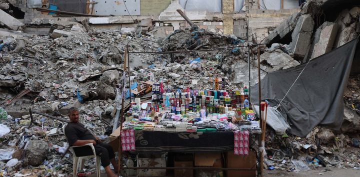 Un palestino se sienta junto a un puesto de cosméticos y productos para el hogar frente a un edificio destruido en la ciudad de Gaza. En octubre se alcanzó un alto el fuego en Gaza entre Israel y Hamás tras dos años de guerra, que se desencadenó por el ataque sin precedentes de milicianos palestinos contra Israel el 7 de octubre de 2023. La segunda fase del alto el fuego, que debía incluir el desarme de Hamás y la retirada gradual de las fuerzas israelíes de Gaza, lleva meses estancada.
