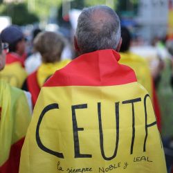 Un manifestante, envuelto en una bandera española con la inscripción "Ceuta siempre noble y leal", participa en una protesta un mes después de la llegada masiva de migrantes a Ceuta, frente al Parlamento español en Madrid. La indignación local divide a Ceuta un mes después de la llegada masiva de migrantes al territorio español del norte de África. Según el gobierno, unos 5.000 migrantes, o al menos 10.000 según las autoridades de Ceuta, permanecen en este pequeño territorio de 18,5 kilómetros cuadrados y 80.000 habitantes, vagando por las calles en busca de comida y durmiendo en la calle y en las playas. | Foto:Thomas Coex / AFP