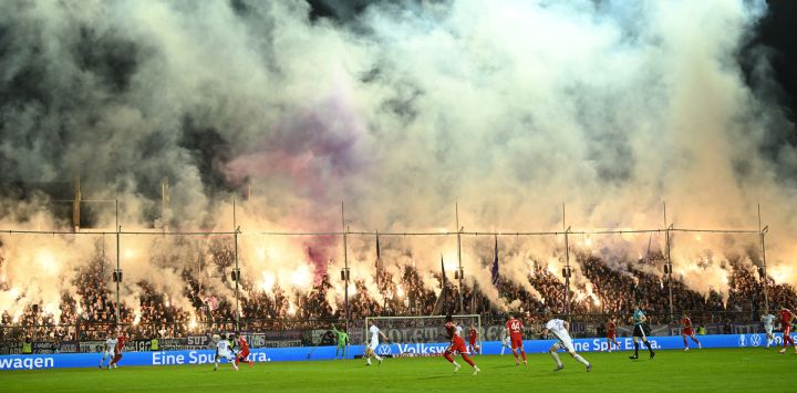 Aficionados del Osnabrück encienden bengalas durante el partido de fútbol de la primera ronda de la Copa de Alemania (DFB Pokal) entre el VfL Osnabrück y el FC Bayern Munich en Osnabrück, Alemania Occidental.