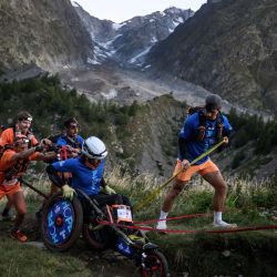 Un corredor de montaña compite en una joellette asistido por un grupo en la arista del Mont Favre durante la 23.ª edición del Ultra Trail du Mont Blanc (UTMB), una carrera de montaña de 174 km que atraviesa Francia, Italia y Suiza en Chamonix, al sureste de Francia. | Foto:JEFF PACHOUD / AFP