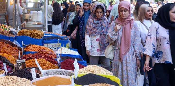 Varias personas pasean frente a tiendas en una zona de mercado de Teherán, Irán.