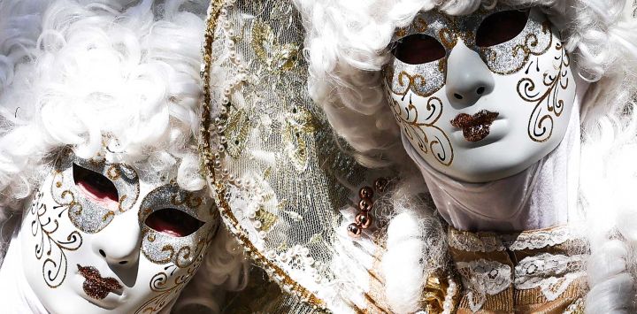 Personas vestidas con trajes venecianos participan en un desfile por las calles de la ciudad durante la 20.ª edición de Les Flaneries au Miroir, un encuentro de trajes de estilo veneciano, en Martigues, sureste de Francia.
