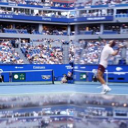 El argentino Francisco Cerundolo saca contra el belga Alexander Blockx, reflejado en el espejo de un equipo de televisión, durante su partido de octavos de final individuales masculinos en el noveno día del torneo de tenis US Open en el Centro Nacional de Tenis USTA Billie Jean King en la ciudad de Nueva York. | Foto:KENA BETANCUR / AFP