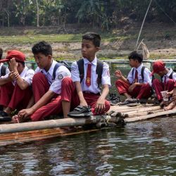 Niños de una escuela primaria sentados en una balsa de bambú cruzan el río Citarum de camino a casa en Saguling, Bandung, provincia de Java Occidental, Indonesia. | Foto:TIMUR MATAHARI / AFP