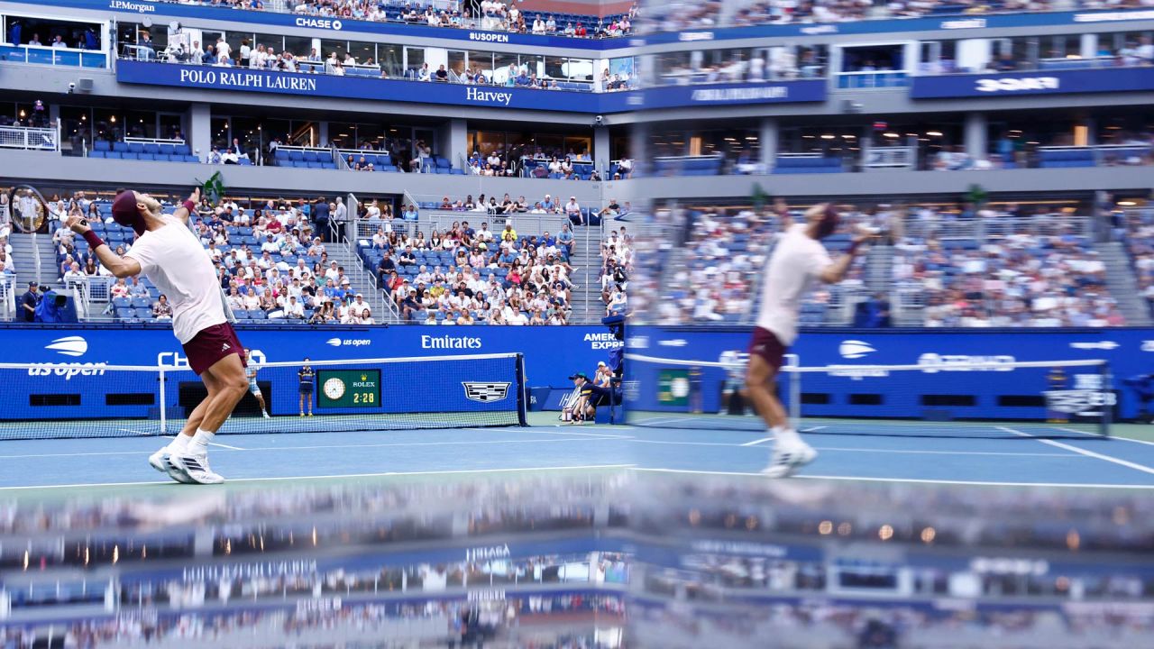 El argentino Francisco Cerundolo saca contra el belga Alexander Blockx, reflejado en el espejo de un equipo de televisión, durante su partido de octavos de final individuales masculinos en el noveno día del torneo de tenis US Open en el Centro Nacional de Tenis USTA Billie Jean King en la ciudad de Nueva York. | Foto:KENA BETANCUR / AFP