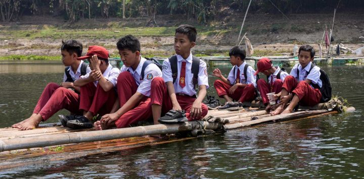 Niños de una escuela primaria sentados en una balsa de bambú cruzan el río Citarum de camino a casa en Saguling, Bandung, provincia de Java Occidental, Indonesia.