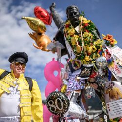Un fan posa junto a la icónica estatua de Freddie Mercury que domina el lago Lemán durante el «Montreux Freddie Day», con motivo del 80.º aniversario del nacimiento del líder de Queen, en Montreux, Suiza. | Foto:FABRICE COFFRINI / AFP