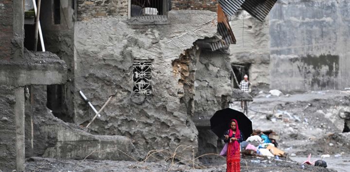 Una mujer camina entre los restos dejados por las repentinas inundaciones en el distrito nepalí de Nuwakot. La enorme ola de agua helada y escombros, provocada por el colapso de un glaciar en la frontera entre China y Nepal, causó la muerte de al menos 939 personas y dejó a cerca de 4.500 desaparecidas; Katmandú ha advertido que los costos de reconstrucción podrían ascender a "miles de millones de dólares".