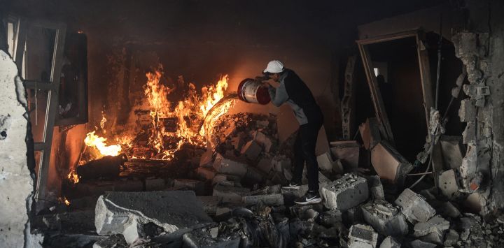 Un hombre palestino intenta sofocar el incendio de una vivienda alcanzada por un ataque israelí —tras una advertencia de evacuación— en el barrio de Al-Rimal, en la ciudad de Gaza. A pesar de un alto el fuego respaldado por Estados Unidos que entró en vigor en octubre de 2025, la violencia no ha cesado en la Franja de Gaza, y Israel sigue atacando a palestinos a quienes califica de militantes.