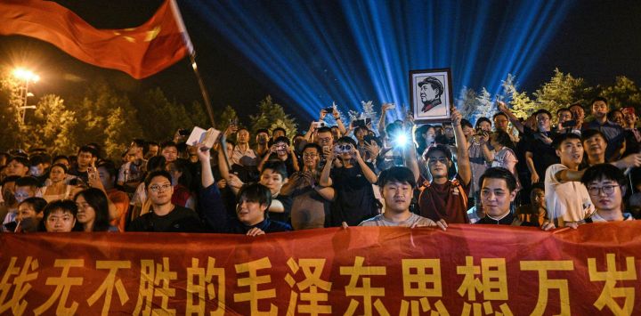 Un hombre sostiene un retrato del fallecido líder comunista Mao Zedong mientras la gente se reúne para rendir homenaje en la Plaza de la Estatua de Bronce de Shaoshan, en la provincia china de Hunan (centro del país), un día antes del 50.º aniversario de su muerte.