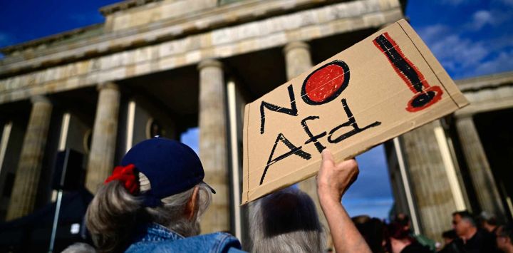 Un participante muestra una pancarta con la inscripción «No AfD» frente a la Puerta de Brandeburgo en Berlín, durante una manifestación bajo el lema «Es hora de actuar: ¡Detengamos a la AfD!», un día después de que el partido de extrema derecha Alternativa para Alemania (AfD) lograra su mayor victoria hasta la fecha, obteniendo el 44 % de los votos en las elecciones estatales de Sajonia-Anhalt. La manifestación fue organizada por Campact y Fridays for Future.