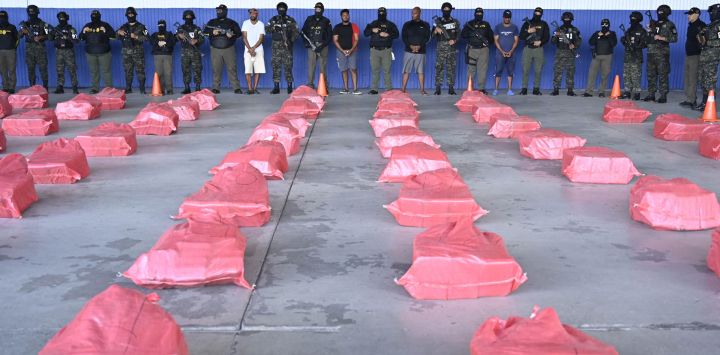 Agentes de policía custodian a cuatro personas detenidas tras una incautación de cocaína, mientras se exhiben los paquetes de la droga en la Base Aérea Hernán Acosta Mejía de Tegucigalpa, Honduras. La Marina y la Fuerza Aérea de Honduras interceptaron una embarcación en aguas del Caribe que transportaba 1,6 toneladas de cocaína y capturaron a sus cuatro tripulantes hondureños, según informó el Ministerio Público.