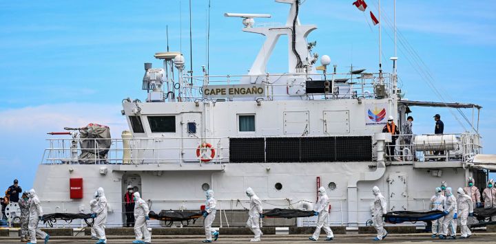 Personal de la Guardia Costera de Filipinas, equipado con trajes de protección, traslada las bolsas con los cuerpos de las víctimas del incendio de un ferry hacia una carpa para su identificación en el puerto de Borac, en la provincia de Palawan. La cifra de fallecidos por el incendio del ferry filipino se elevó a 76, después de que la Guardia Costera confirmara el hallazgo de otros 41 cuerpos a bordo de la embarcación calcinada.