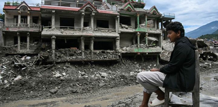 Un hombre está sentado frente a su casa dañada y cubierta de lodo tras unas inundaciones repentinas en Trishuli, en el distrito nepalí de Nuwakot.