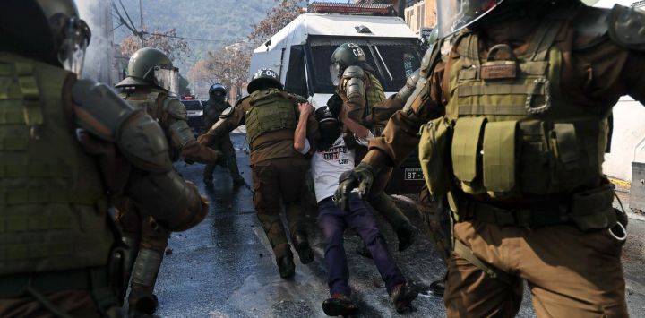 Carabineros de Chile arrastran a un manifestante durante enfrentamientos en el marco de una marcha conmemorativa hacia el Cementerio General en honor a las víctimas de la dictadura de Augusto Pinochet (1973-1990), en Santiago.