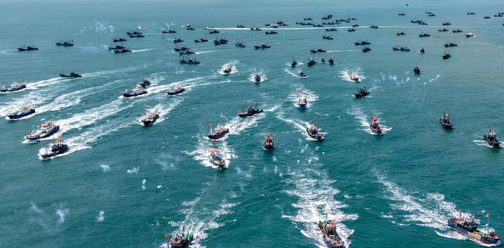 Una vista aérea muestra barcos pesqueros zarpando hacia alta mar desde el puerto pesquero de Jimiya, en la Nueva Zona de la Costa Oeste de Qingdao, provincia de Shandong, este de China, al comenzar la temporada de pesca de otoño tras una veda estival de cuatro meses.