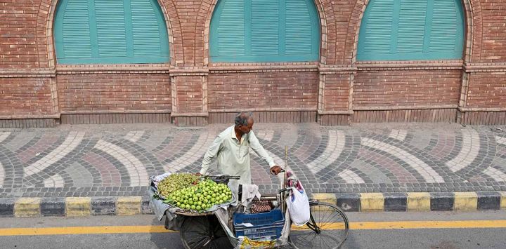 Un vendedor de fruta empuja su bicicleta por una calle de Lahore.