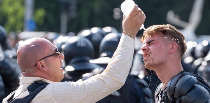 Un gendarme recibe ayuda de un compañero para que le laven los ojos mientras manifestantes se enfrentan a gendarmes durante una manifestación de agricultores y pastores en Bucarest, Rumania.
