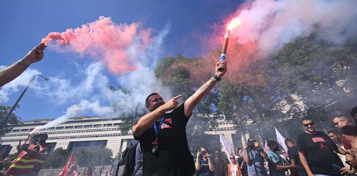 Un manifestante sostiene una bengala durante una protesta convocada por varios sindicatos del sector eléctrico y del gas contra un plan gubernamental para eliminar la 