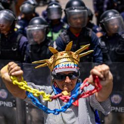 Un familiar de un preso político se manifiesta frente a un cordón policial durante una protesta para exigir la liberación de detenidos y denunciar el incumplimiento de las liberaciones de presos anunciadas previamente, cerca del Palacio Presidencial de Miraflores en Caracas, Venezuela. | Foto:Maxwell Briceno / AFP