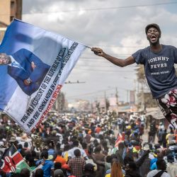 Un partidario de Edwin Sifuna —figura de la oposición keniana y senador por Nairobi—, perteneciente a la coalición Linda Mwananchi (Proteger a los Ciudadanos), sostiene una bandera que presenta a Sifuna como el próximo presidente de Kenia, mientras una gran multitud sigue una caravana opositora en Nairobi. | Foto:LUIS TATO / AFP