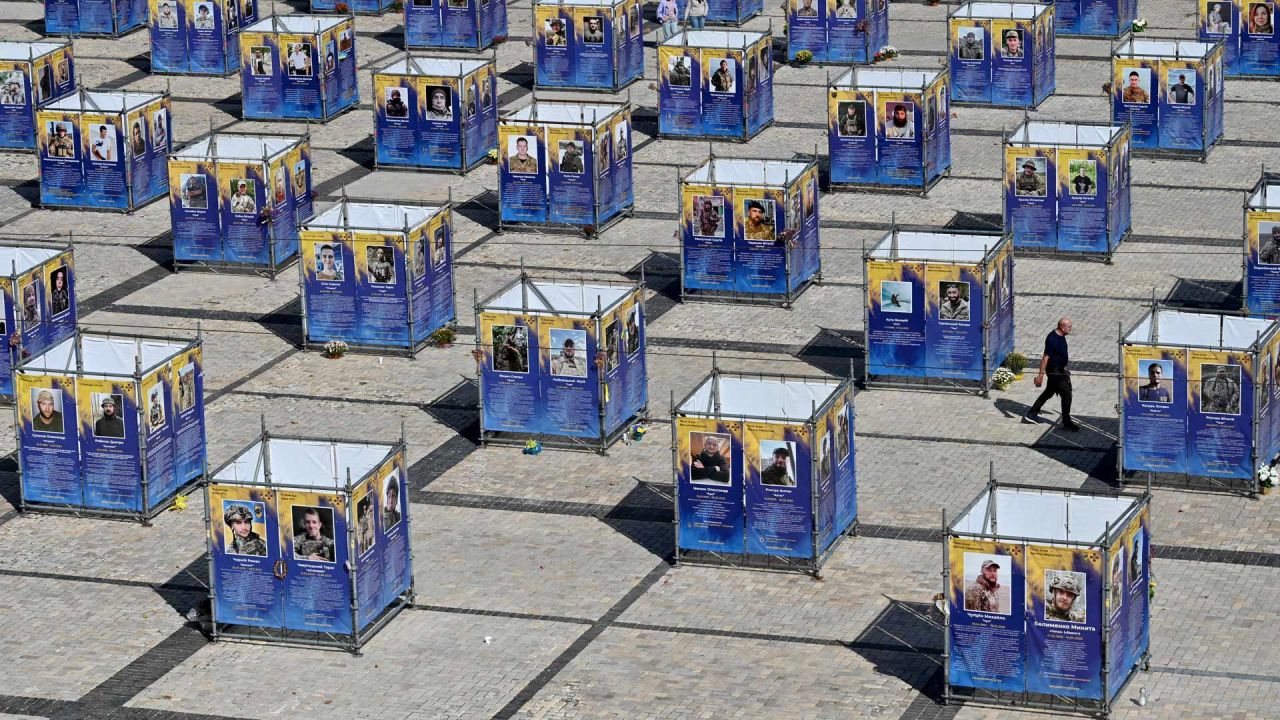 Un hombre camina entre paneles que exhiben retratos de combatientes caídos de la Brigada Azov, instalados en la plaza de Santa Sofía, en el centro de Kiev, en medio de la invasión rusa de Ucrania. | Foto:SERGEI SUPINSKY / AFP