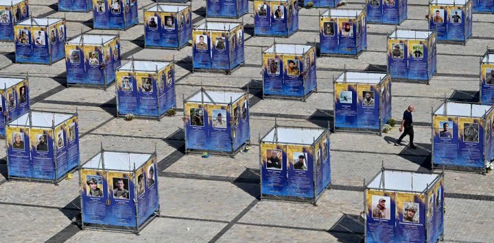 Un hombre camina entre paneles que exhiben retratos de combatientes caídos de la Brigada Azov, instalados en la plaza de Santa Sofía, en el centro de Kiev, en medio de la invasión rusa de Ucrania.