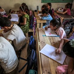 Alumnos palestinos asisten a clase en una escuela de la ciudad de Gaza, sentados en pupitres fabricados con palés de madera reutilizados y restos de madera. Desde que estalló la guerra en Gaza en octubre de 2023, la gran mayoría de las escuelas y centros educativos de la Franja han sufrido daños o han sido destruidos por ataques aéreos o de artillería, dejando a decenas de miles de niños sin acceso a una educación formal. | Foto:OMAR AL-QATTAA / AFP