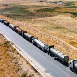Esta vista aérea muestra camiones cisterna de petróleo detenidos mientras los residentes bloquean la autopista M4 en Tal Tamr, en la provincia nororiental siria de Hasaka, impidiendo su paso desde el noreste de Siria hacia las refinerías gubernamentales en protesta por las recientes subidas de los precios del combustible. | Foto:DELIL SOULEIMAN / AFP