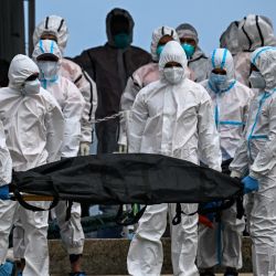 Personal de la Guardia Costera de Filipinas, equipado con trajes de protección, transporta una bolsa con restos humanos para su identificación en el puerto de Borac, en Coron, provincia de Palawan. La cifra de fallecidos en el incendio de un transbordador filipino se elevó a 76, después de que la Guardia Costera confirmara el hallazgo de otros 41 cuerpos a bordo de la embarcación calcinada. | Foto:JAM STA ROSA / AFP