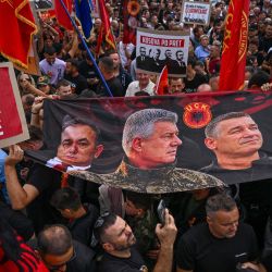 Un grupo de albanokosovares sostiene una pancarta con imágenes que muestran (de izquierda a derecha) al excomandante del ELK Rexhep Selimi, al exlíder político del ELK Hashim Thaci, al exalto mando y jefe de inteligencia del ELK Kadri Veseli y al exportavoz del ELK Jakup Krasniqi durante la "Marcha por la Libertad" en Pristina, cuatro días antes de que se anuncie el veredicto del juicio por crímenes de guerra contra Hashim Thaci. | Foto:Armend Nimani / AFP