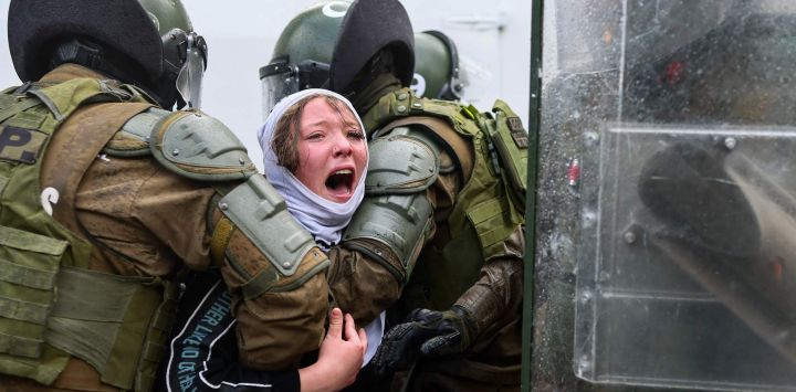 Carabineros de Chile detienen a una mujer durante una marcha en memoria de las víctimas de la dictadura de Augusto Pinochet (1973-1990), con motivo del 53.º aniversario del golpe de Estado que llevó a Pinochet al poder, en Santiago.