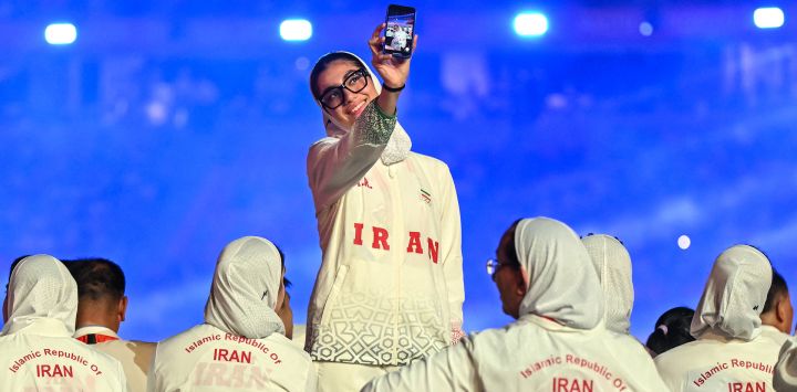 Un miembro de la delegación de Irán se toma una selfi durante el desfile de la ceremonia de inauguración de los Juegos Asiáticos de 2026 en el Estadio Paloma Mizuho de Nagoya.