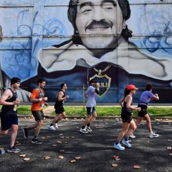  Corredores compiten en el Maratón Internacional de Buenos Aires mientras pasan frente a un mural que representa a la leyenda del fútbol argentino Diego Maradona, en el barrio de La Boca, Buenos Aires, el 20 de septiembre de 2026. | Foto:AFP