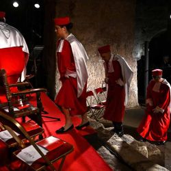 Los *jurats* de Saint-Émilion —miembros de la *Jurade*, la cofradía báquica del vino de Saint-Émilion—, ataviados con sus trajes ceremoniales, ocupan sus puestos para una ceremonia de investidura en la iglesia monolítica de Saint-Émilion, en el suroeste de Francia, el 20 de septiembre de 2026. La *Jurade* de Saint-Émilion proclama simbólicamente la fecha de inicio de la vendimia en septiembre, durante una jornada marcada por procesiones, una misa en la iglesia católica y una ceremonia de investidura en la iglesia monolítica. | Foto:AFP
