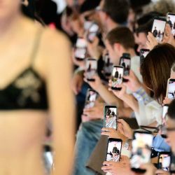 Los asistentes sostienen sus teléfonos inteligentes durante el desfile de la colección de Prada, en el marco de la Semana de la Moda de Milán (temporada Primavera/Verano 2027 para mujer). | Foto:STEFANO RELLANDINI / AFP