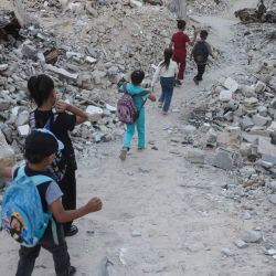 Niños palestinos caminan hacia la escuela entre los escombros de edificios destruidos al comenzar el año escolar en Jan Yunis, en el sur de la Franja de Gaza. | Foto:Bashar Taleb / AFP