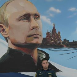 Un miembro del Ministerio de Emergencias de Rusia está sentado bajo un mural que representa al presidente ruso, Vladímir Putin, durante las elecciones parlamentarias de Rusia en un colegio electoral de Donetsk, zona de Ucrania bajo control ruso, en medio del conflicto ruso-ucraniano en curso. | Foto:AFP