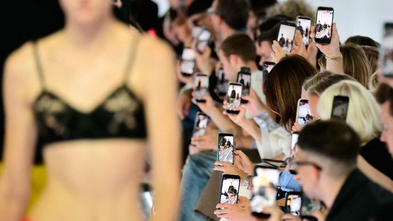 Los asistentes sostienen sus teléfonos inteligentes durante el desfile de la colección de Prada, en el marco de la Semana de la Moda de Milán (temporada Primavera/Verano 2027 para mujer). | Foto:STEFANO RELLANDINI / AFP