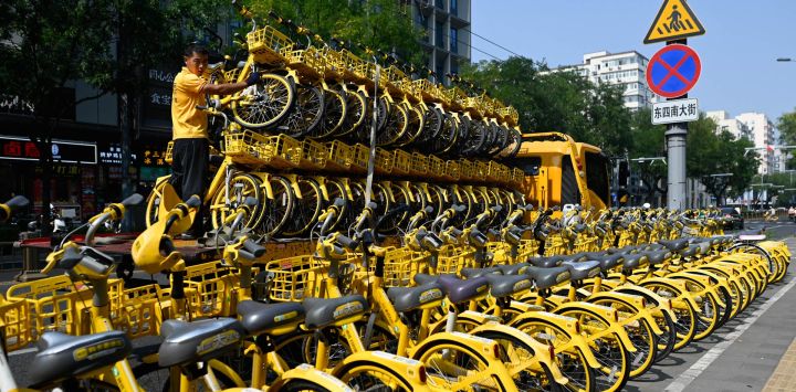 Un trabajador descarga bicicletas de uso compartido de un camión en una calle de Pekín.